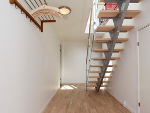 A modern interior with a wooden floor, a staircase with metal railings, and a light fixture. - 7 Person Holiday Home in Stege (Stege)