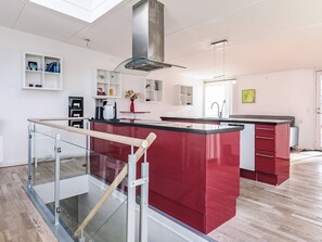 A modern kitchen with a central island, stainless steel range hood, and built-in shelving. - 7 Person Holiday Home in Stege (Stege)