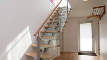 A modern staircase with glass railings and wooden steps leading to a door.