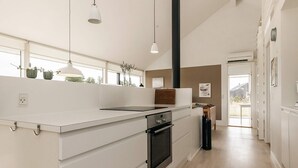 Una cuina moderna amb una illa central, forn integrat i il·luminació penjant.