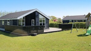 A modern building with a sloped roof, large windows, and a fenced outdoor area with a playground. - Spacious Retreat With Whirlpool - By Traum Ferienwohnungen (Hadsund)
