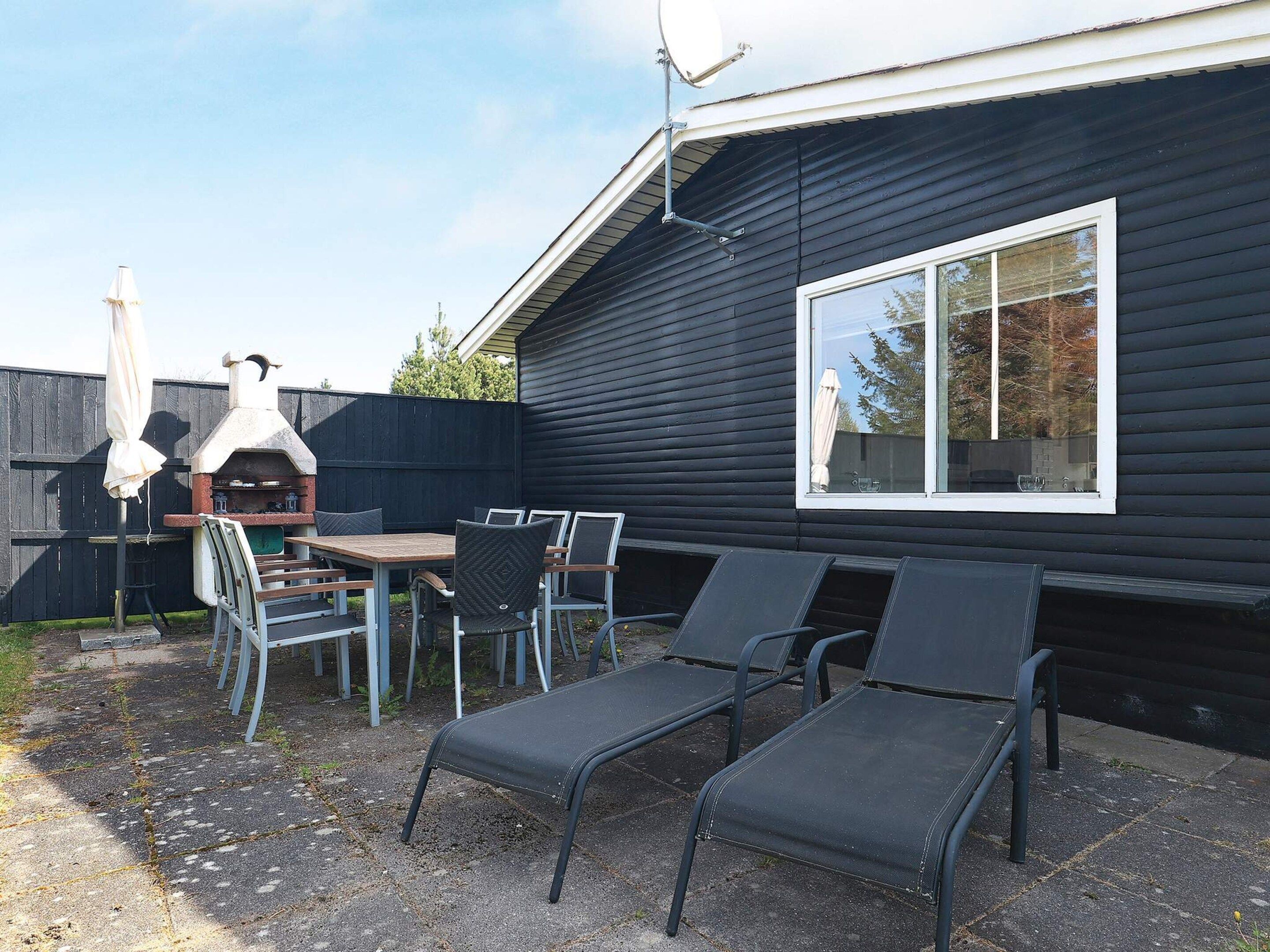 Une terrasse avec une table et des chaises, un barbecue et une fenêtre.