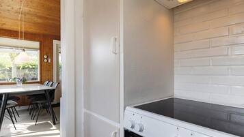 A kitchen with a white brick wall, a stove with control knobs, and a dining area with a table and chairs.