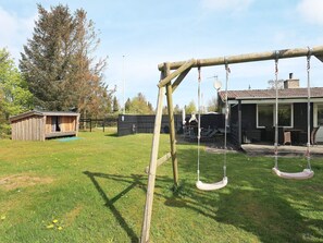 A backyard with a swing set, a wooden shed, and a barbecue area. - 6 Person Holiday Home in Hadsund (Hadsund)