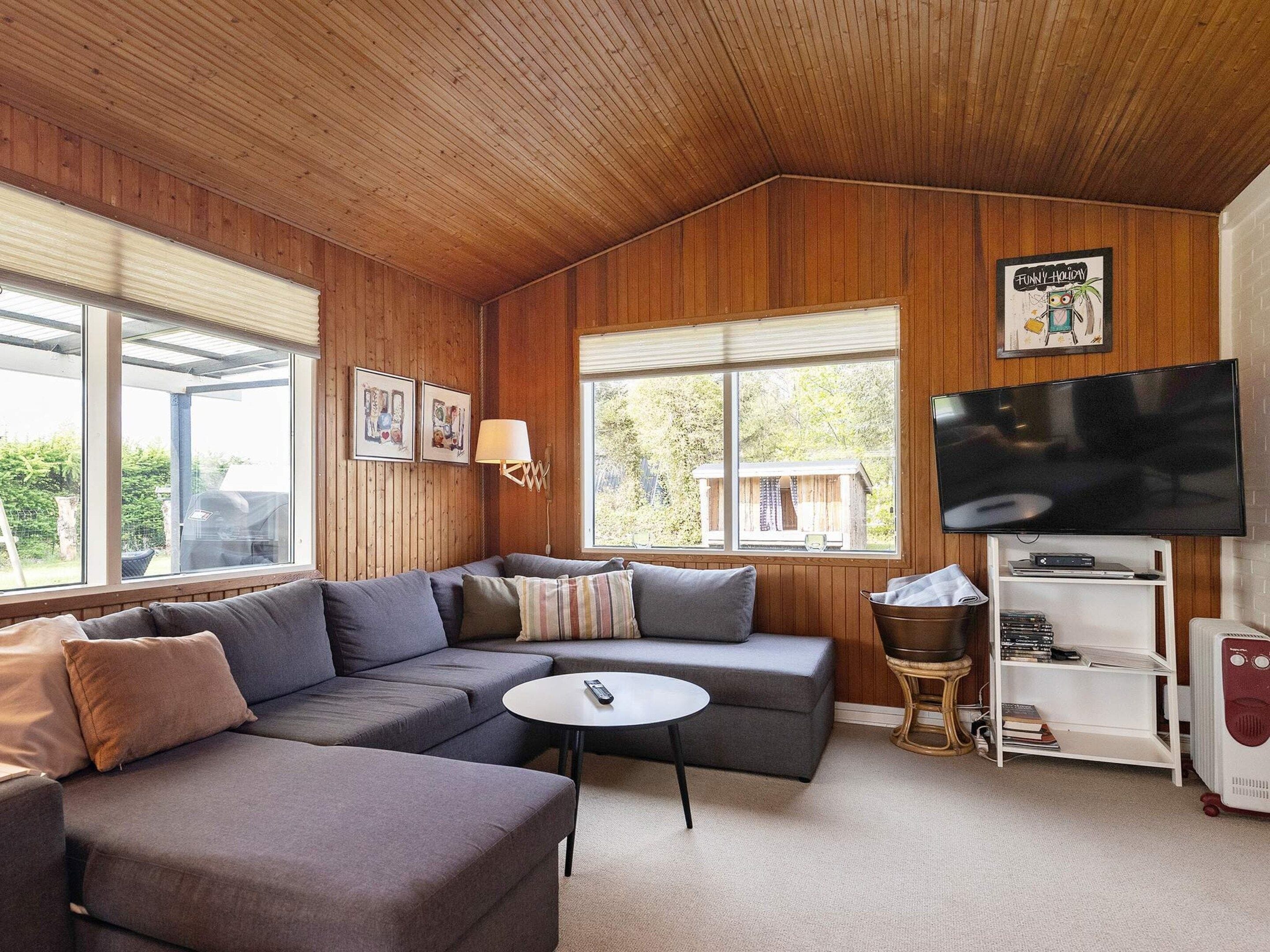 A cozy living room with a sectional sofa, a round coffee table, and a television.