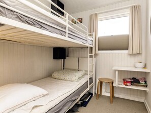 A bunk bed room with a window, a small stool, and a shelf with items.