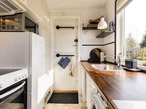 A compact kitchen with a built-in oven, a washing machine, and a sink. - 6 Person Holiday Home in Hadsund (Hadsund)