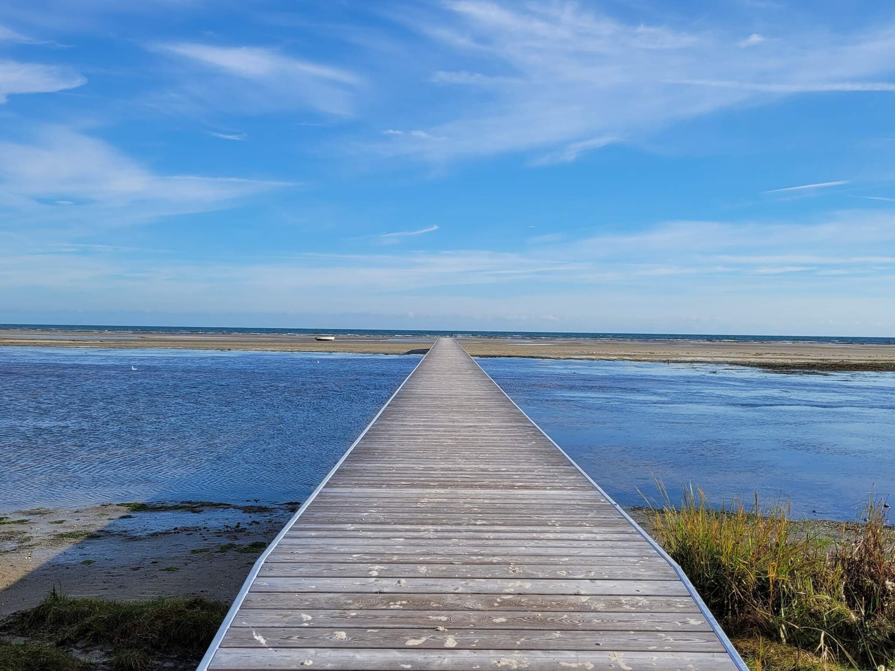A wooden pier extending into a body of water with a clear sky above.