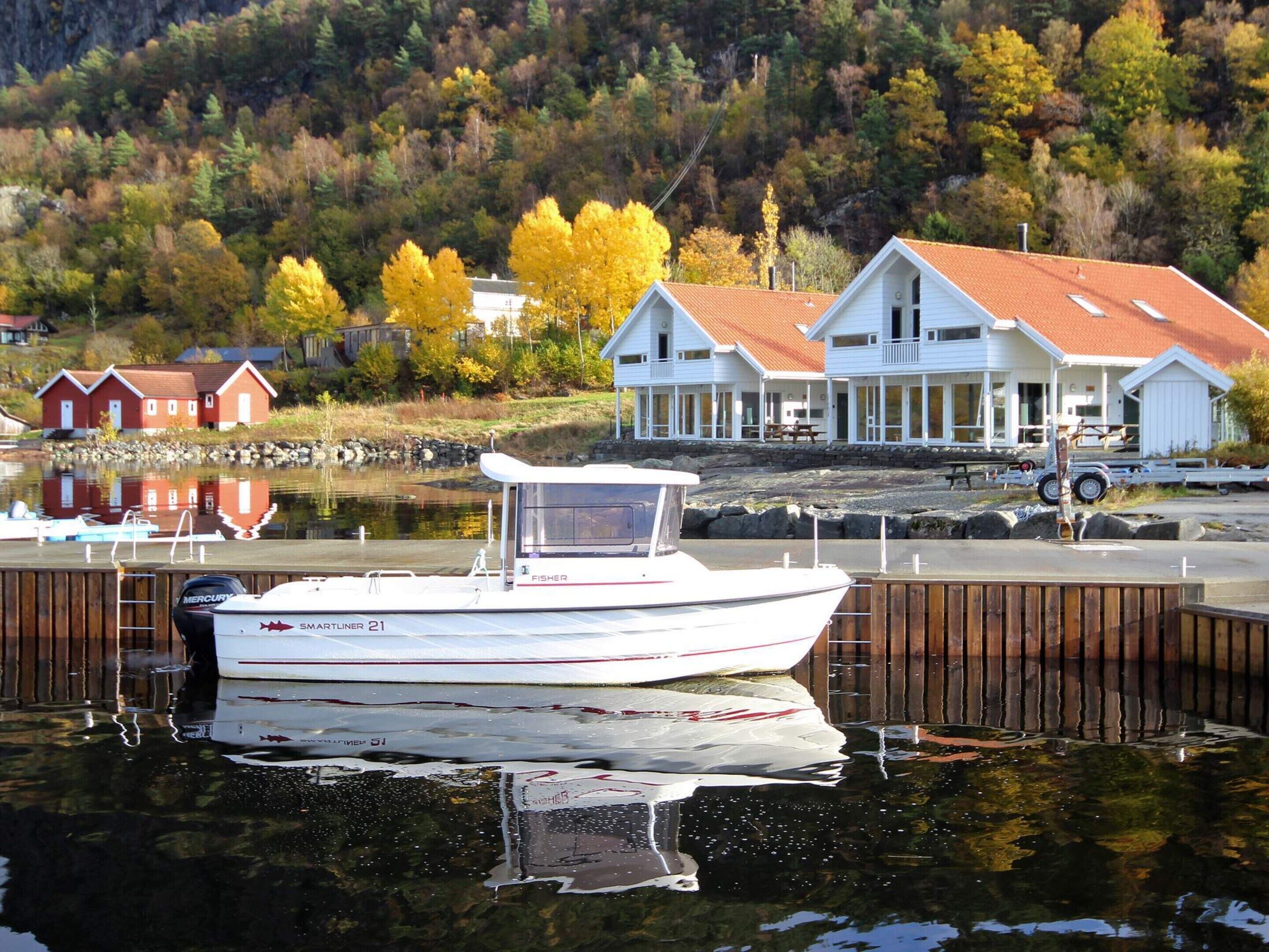 A boat docked at a pier with a waterfront view of houses and trees.