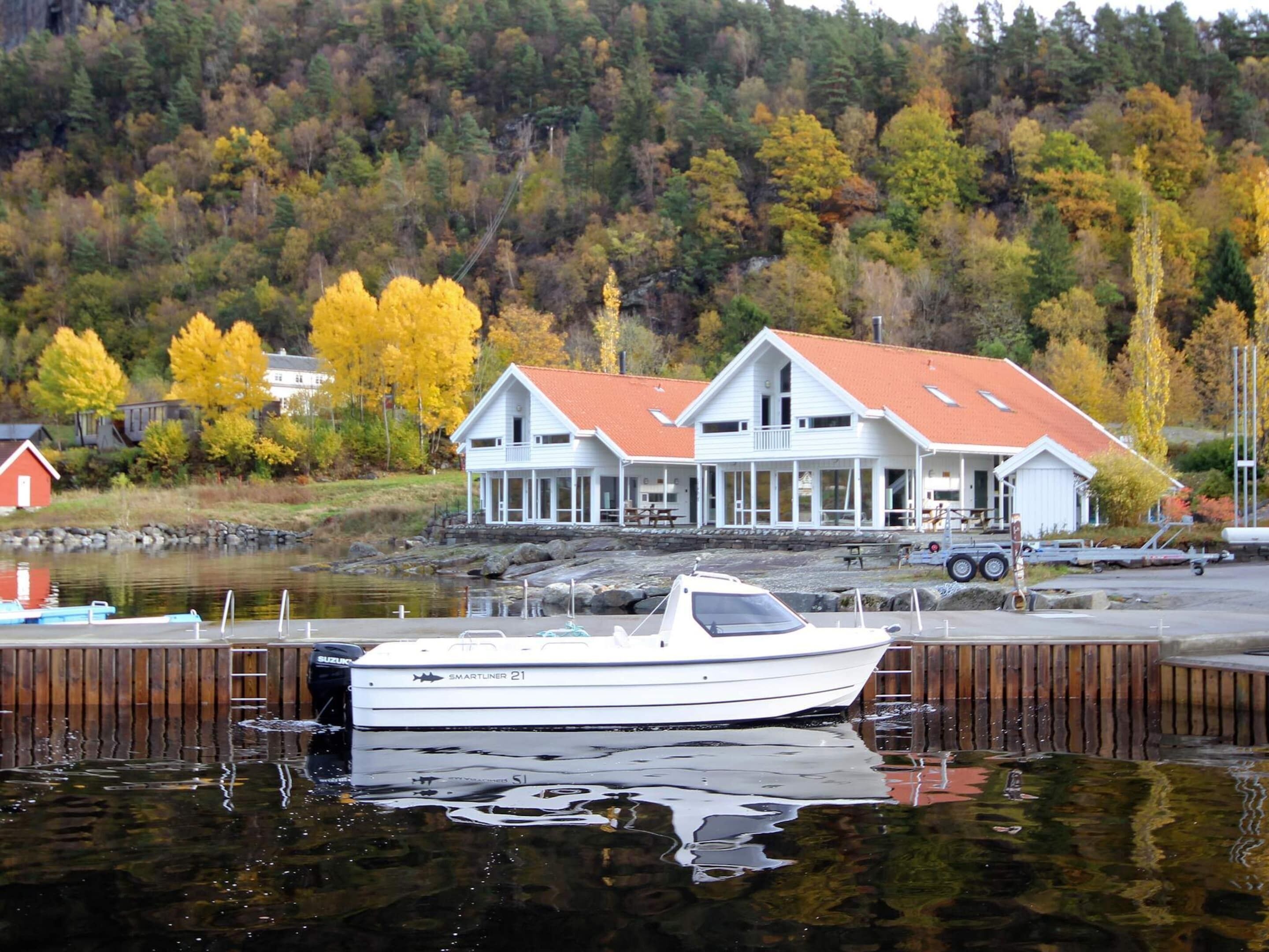 A white boat docked at a pier with a house in the background.