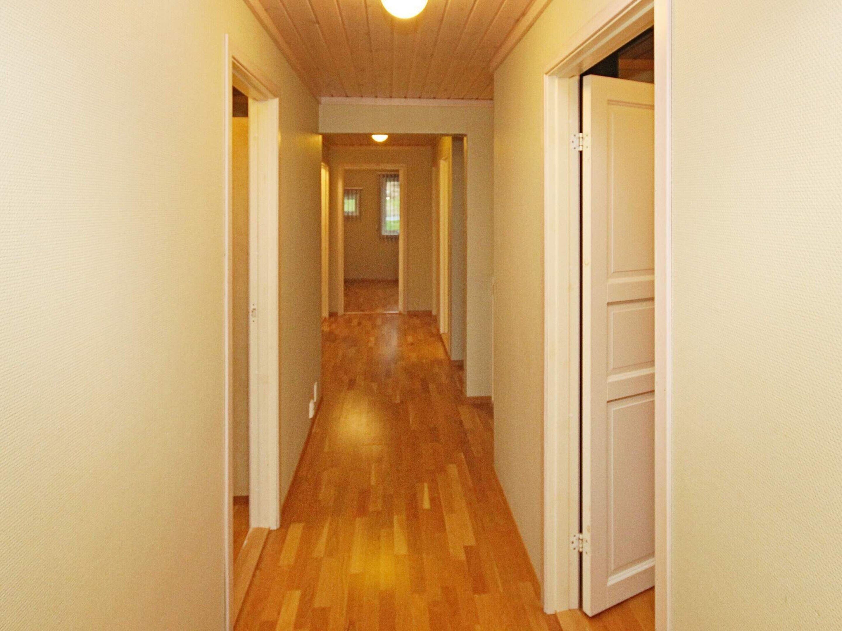 A narrow hallway with wooden flooring and white walls.