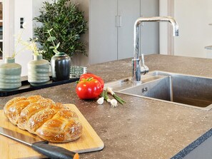 A kitchen counter with a bread loaf, a tomato, and a knife. - 5 Star Holiday Home in Harboore (Harboore)