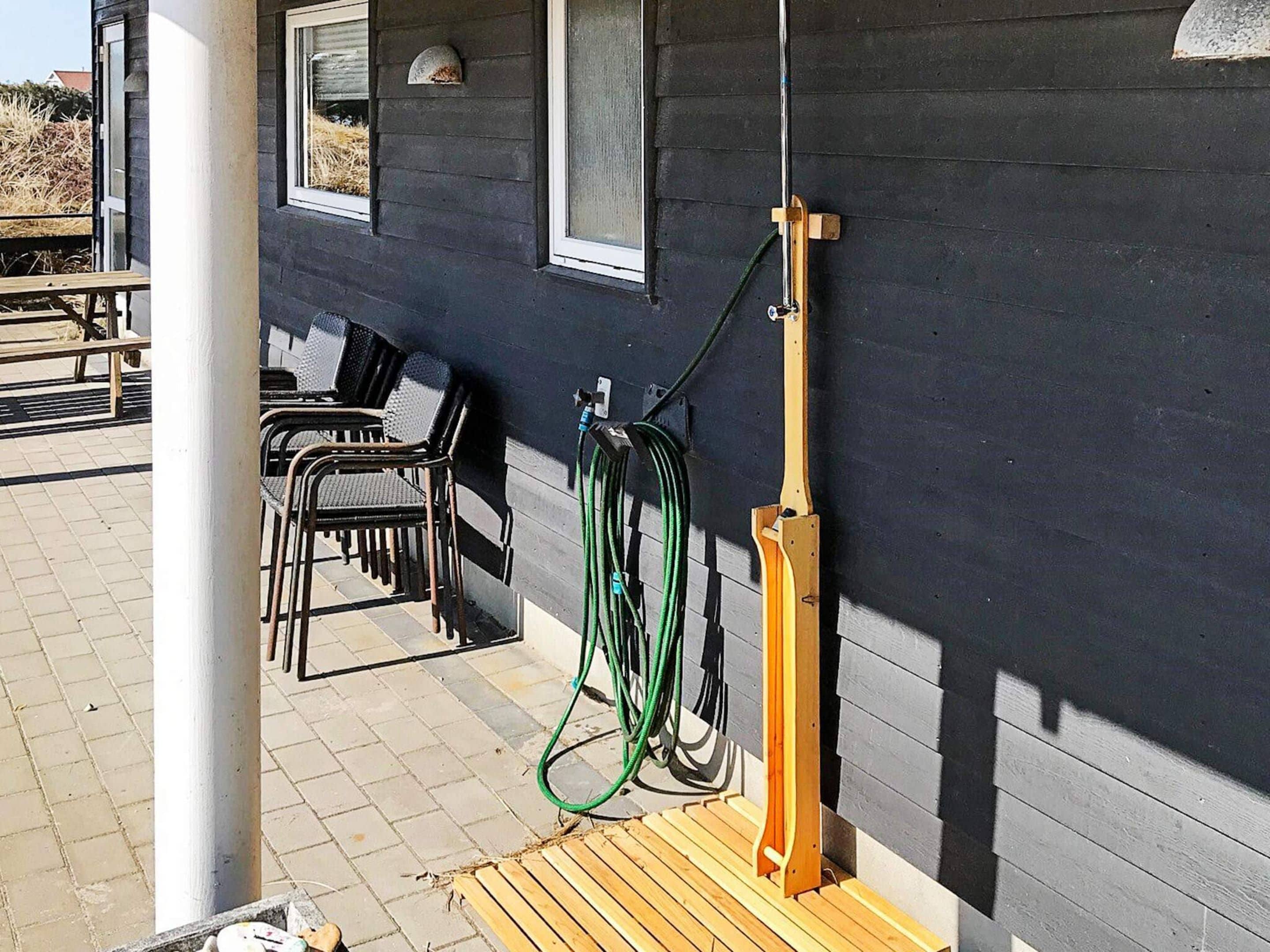 En patio med udendørs møbler, slangreels og et træterrasse.
