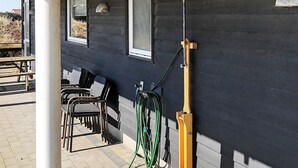 Un patio con mobiliario exterior, un carrete para manguera y una terraza de madera.