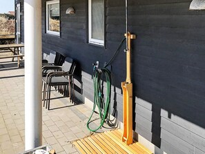 Un patio con mobiliario exterior, un carrete para manguera y una terraza de madera.