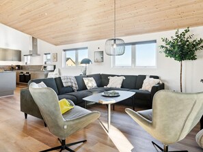 A modern living space with a sofa set, two armchairs, a coffee table, and a dining table.