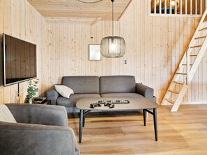 A cozy living room with a sofa, a coffee table, and a TV mounted on the wall.