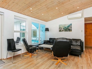 A modern living room with a wooden ceiling, a pool view, and a mountain landscape painting.