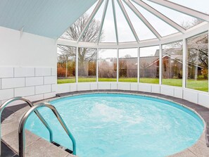 A swimming pool with a glass enclosure, surrounded by a white tiled wall and large windows. - 4 Star Holiday Home in Juelsminde (Horsens)