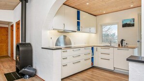 Uma cozinha moderna com uma lareira a lenha, armários brancos e uma janela com vista para o exterior.