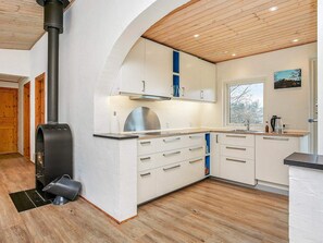 Una cucina moderna con stufa a legna, pensili bianchi e una finestra con vista all'esterno.