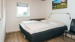 Quarto com uma cama, janela, cadeira e um quadro na parede.