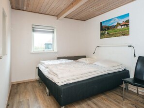 Una camera da letto con un letto, una finestra, una sedia e un quadro appeso al muro.
