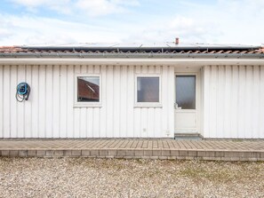 Un bâtiment blanc avec un toit recouvert de tuiles, une porte et deux fenêtres.
