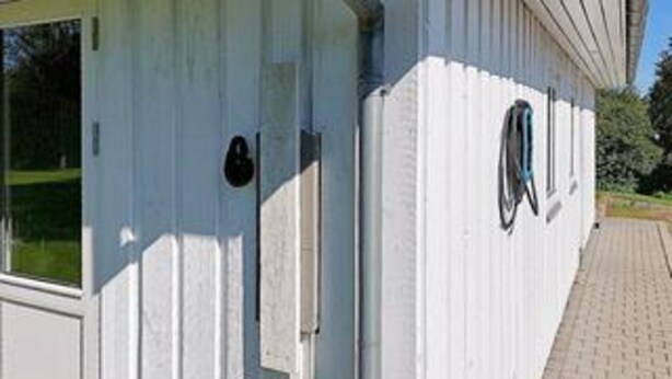 Edifício branco com janela, porta e pequena área externa com uma cadeira de rodas.
