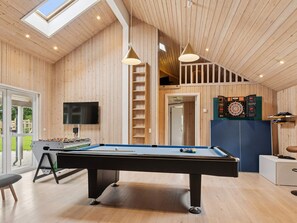 A room with a pool table, a television, and a dartboard.