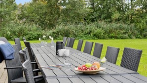 A wooden table set for a meal with chairs, a bowl of fruit, a pitcher, and glasses. - 5 Star Holiday Home in Idestrup (Idestrup)