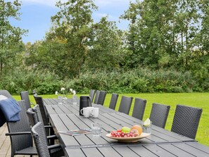A wooden table set for a meal with chairs, a bowl of fruit, a pitcher, and glasses. - 5 Star Holiday Home in Idestrup (Idestrup)