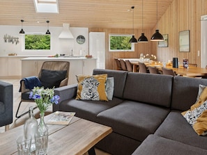 A modern interior with a sofa, dining table, and kitchen area. - 5 Star Holiday Home in Idestrup (Idestrup)