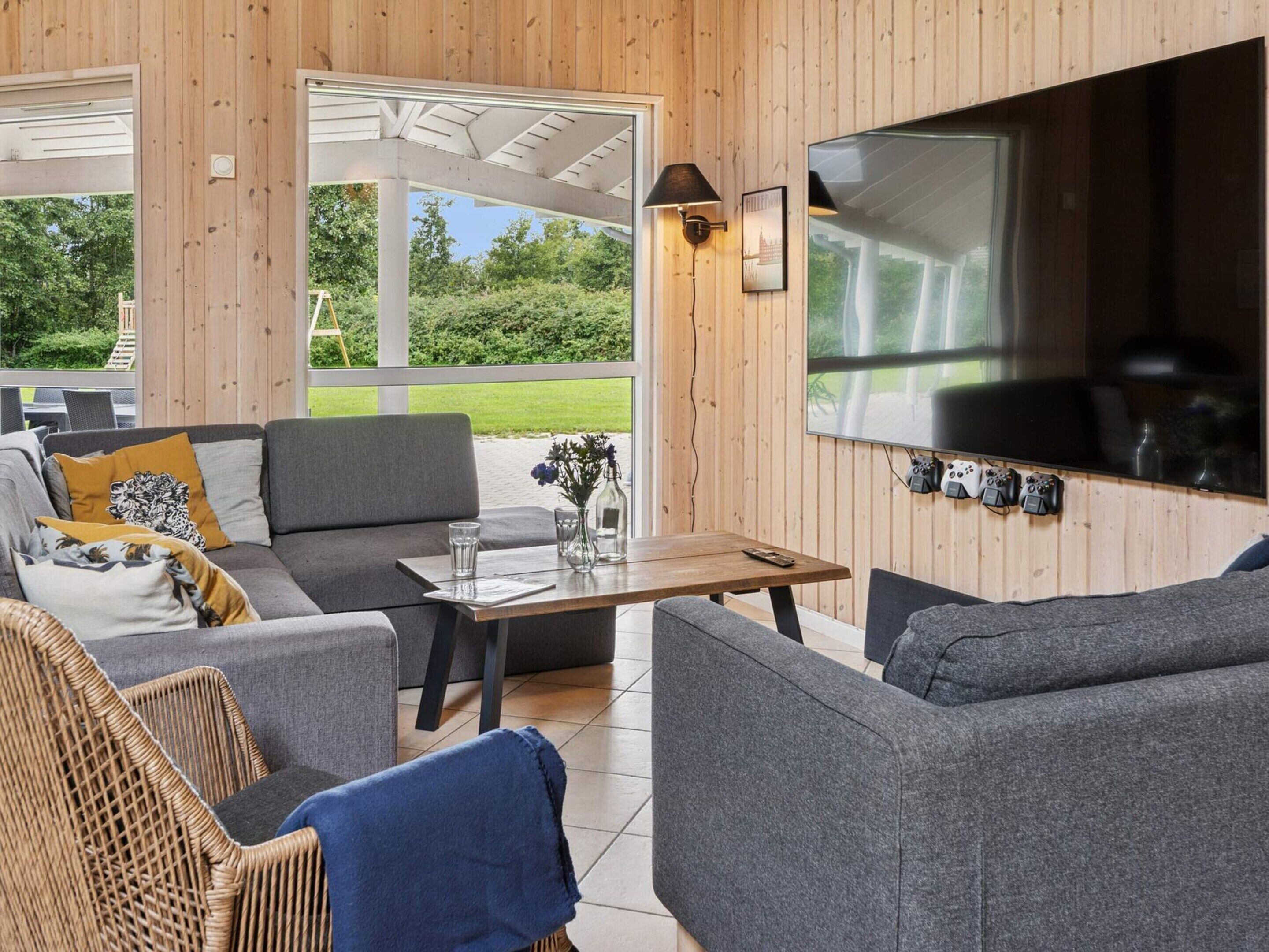A cozy outdoor seating area with a TV, comfortable sofas, and a table with drinks.