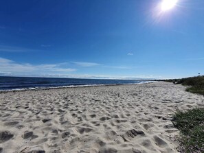 A sandy beach with footprints, a clear sky, and the ocean.