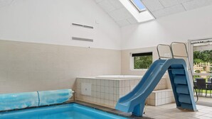 A swimming pool with a blue slide, a window, and a skylight. - 5 Star Holiday Home in Idestrup (Idestrup)