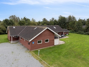 A two-story building with a sloped roof, a covered porch, and a well-maintained lawn. - 5 Star Holiday Home in Idestrup (Idestrup)