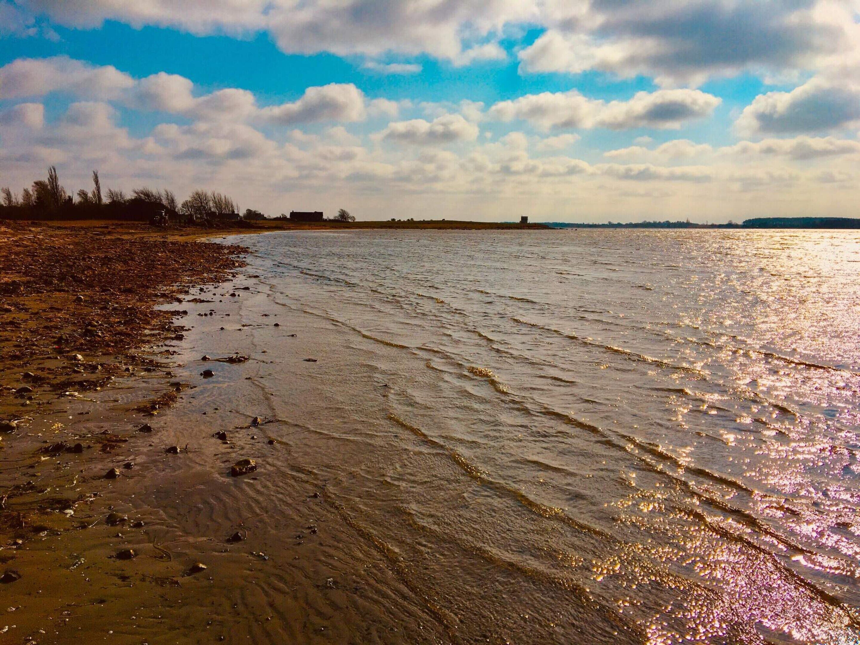 A beach with a sandy shore and gentle waves.