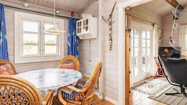 A cozy room with a round table, wicker chairs, and a hanging chair. - 4 Person Holiday Home in Lokken (Lokken)