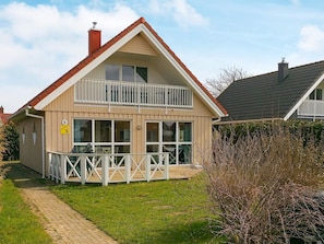 A two-story house with a balcony, a visible number '6' sign, and a paved driveway. - Holiday Home in Gilleleje (Gelting)