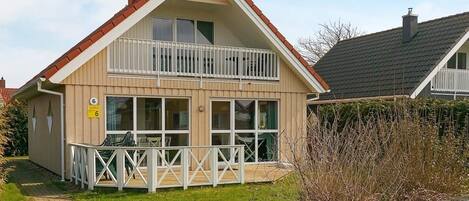 Une maison à deux étages avec un balcon, un panneau indiquant clairement le numéro « 6 », et un chemin pavé menant à l’entrée.