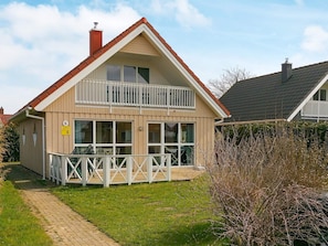 A two-story house with a balcony, a visible number '6' sign, and a paved pathway leading to the entrance. - Holiday Home in Gilleleje (Gelting)