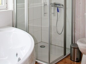 Bathroom features a glass-enclosed shower with handheld showerhead and wall-mounted faucet, alongside a bathtub with visible drain.
