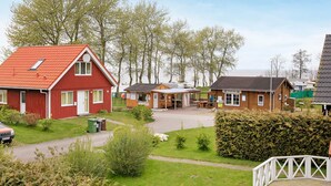 A red building with a sloped roof, a wooden structure with a roof, and a white fence. - Holiday Home in Gilleleje (Gelting)