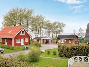 A red building with a sloped roof, a wooden structure with a roof, and a white fence. - Holiday Home in Gilleleje (Gelting)