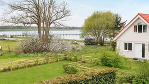 A residential area with a house, a wooden fence, and a tree with white blossoms. - Holiday Home in Gilleleje (Gelting)