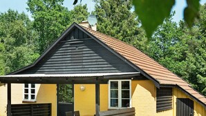 Ein gelbes Gebäude mit schwarzem Dach, einer überdachten Terrasse und einer Garage.