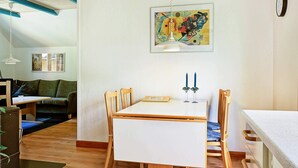 Ein Essbereich mit einem weißen Tisch, Holzstühlen und einem Gemälde an der Wand.