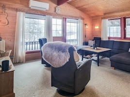 Un acogedor interior de cabaña de madera con un sillón mullido, un sofá y una mesa de comedor.