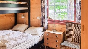 A wooden room with a bed, a dresser, a chair, and a window with a view of greenery. - 6 Person Holiday Home in Aseral (Aseral)